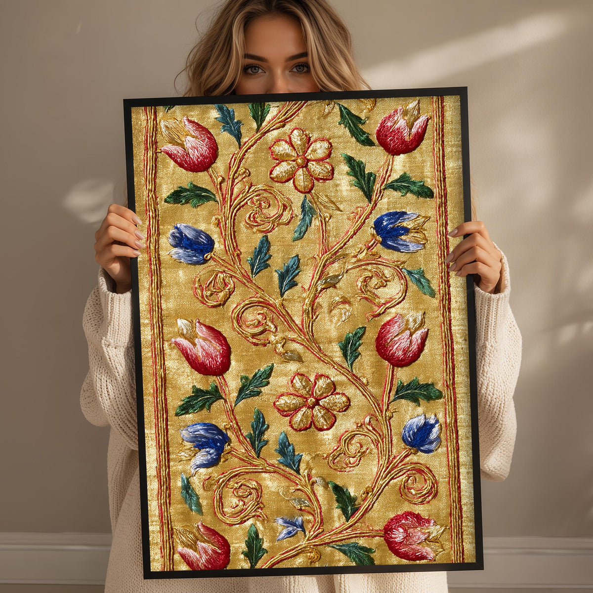 A woman holds up a framed picture with a floral design, featuring red, blue, and green flowers and leaves.