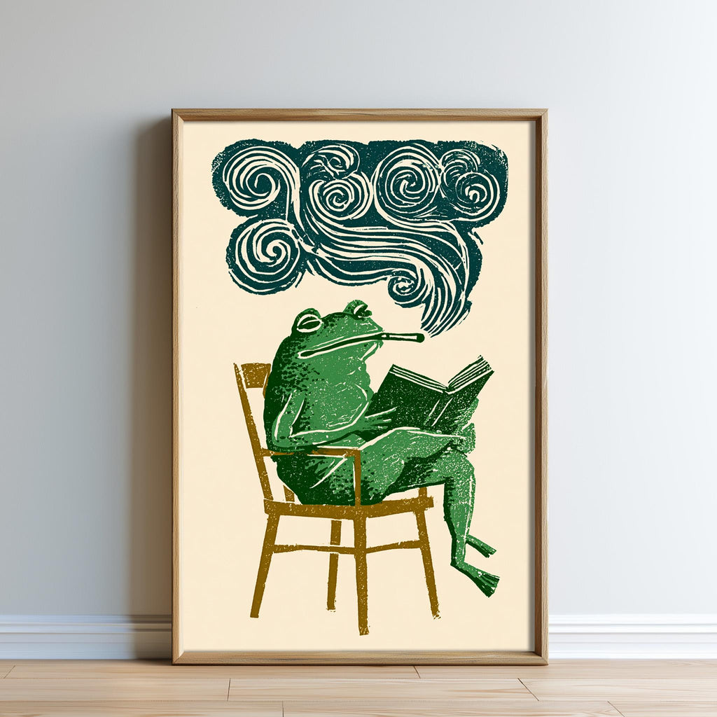 The image is a framed illustration depicting a green frog sitting in a chair and reading a book, with a cloud-like shape above the frog.
