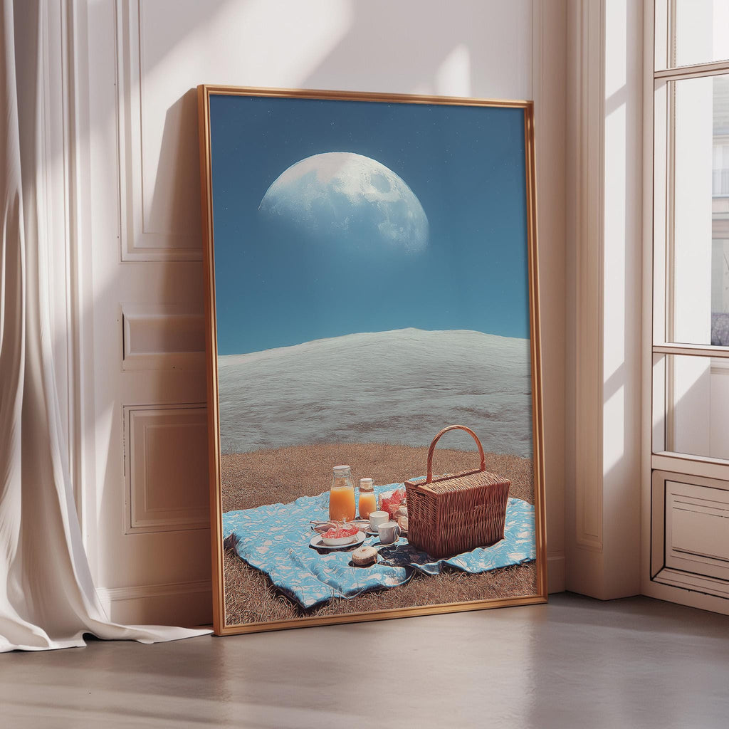 A large framed picture depicting a picnic scene with a basket, food, and drinks on a blanket, set against a backdrop of a moon and a blue sky.