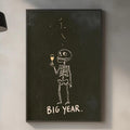 a kitchen counter with various items such as a cutting board, a bottle, and a plant. Above the counter, there is a framed drawing of a skeleton holding a wine glass, accompanied by the text "BIG YEAR."