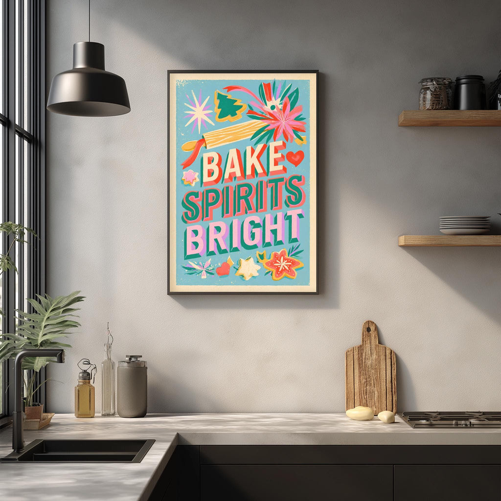 a kitchen counter with various kitchen items, such as a cutting board, a sink, and a potted plant. Above the counter, there is a framed poster with a colorful design and text that reads "Bake, Spirits, Bright".