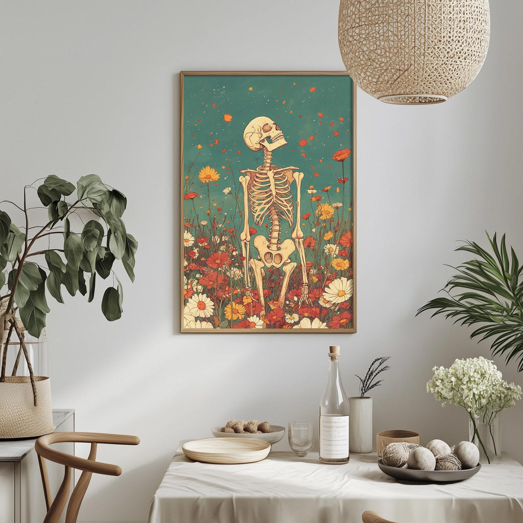 a dining table with a white tablecloth, a bowl of fruit, a bottle, and a vase with flowers. Above the table, there is a framed artwork depicting a skeleton standing in a field of flowers.