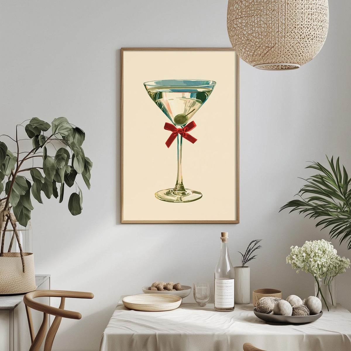 a framed illustration of a martini glass with a red ribbon, hanging on a wall above a dining table with various decorative items and plants.