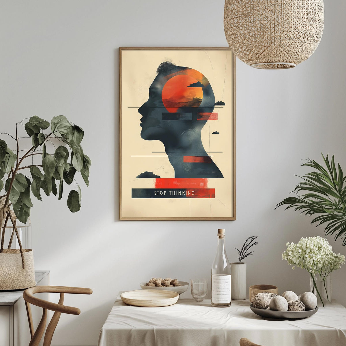 a framed poster with a silhouette of a person's head and the text "STOP THINKING" displayed on it, hanging on a wall above a dining table with various decorative items and plants.