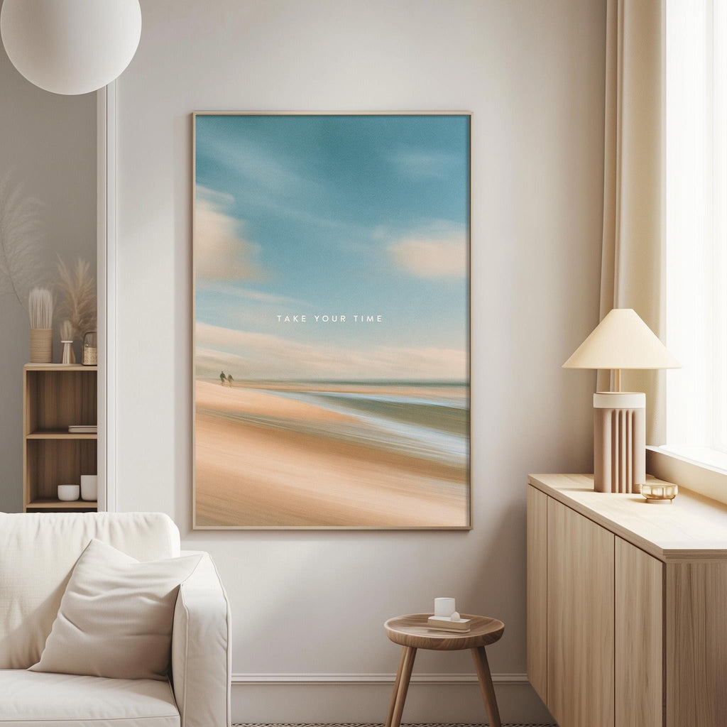 a living room with a large framed picture of a beach scene hanging on the wall. The picture has a blue sky and clouds, and the words "Take your time" are written on it. The room also includes a white couch, a small table, and a lamp.