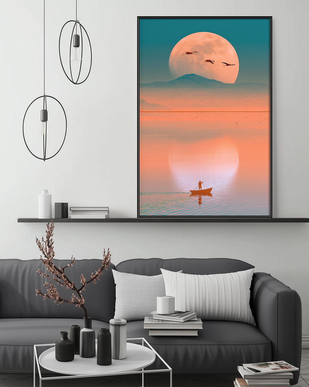 a large, colorful painting of a boat on a lake, with a large moon in the background. The painting is hanging on a wall above a gray couch, which has a coffee table in front of it. The room also has a shelf with various decorative items, and a pendant light fixture hanging above the couch.