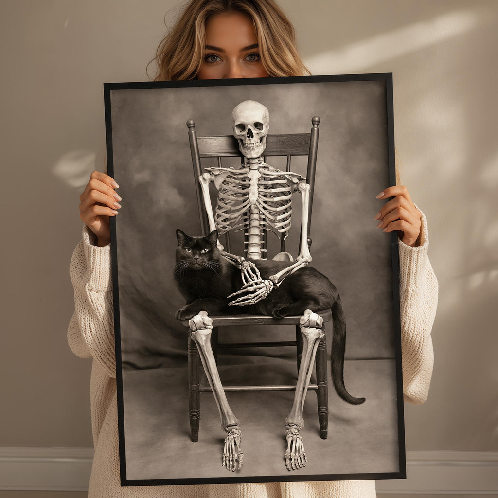 A woman holds a framed image of a skeleton with a cat sitting on its lap.