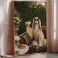 A large framed print depicting a dog sitting on a plaid couch, holding a cup of coffee, with a vase of flowers and a newspaper on a table in the background.