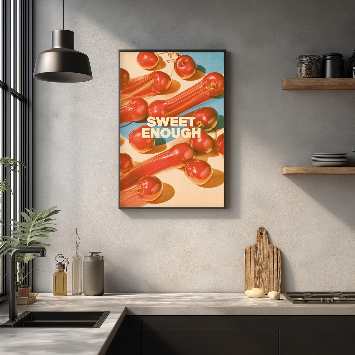 a kitchen counter with various kitchen items, including a cutting board, a bottle, and a bowl. Above the counter, there is a framed poster with the text "Sweet Enough" displayed prominently.