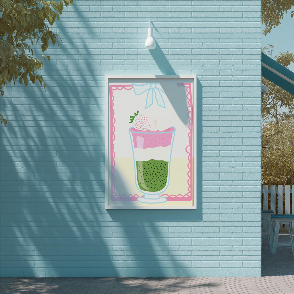 A framed illustration of a strawberry milkshake is displayed on a blue brick wall, with a white light fixture above it.