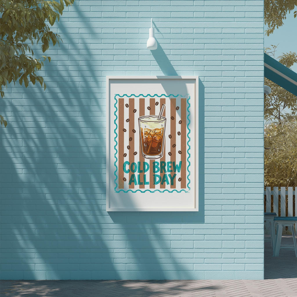A framed poster with a picture of a glass of iced coffee and the text "COLD BREW ALL DAY" is displayed on a blue brick wall.