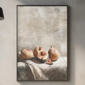 a kitchen counter with a framed painting of fruit, including peaches and a wooden cutting board, as well as various kitchen items such as a potted plant, a vase, and a bottle.