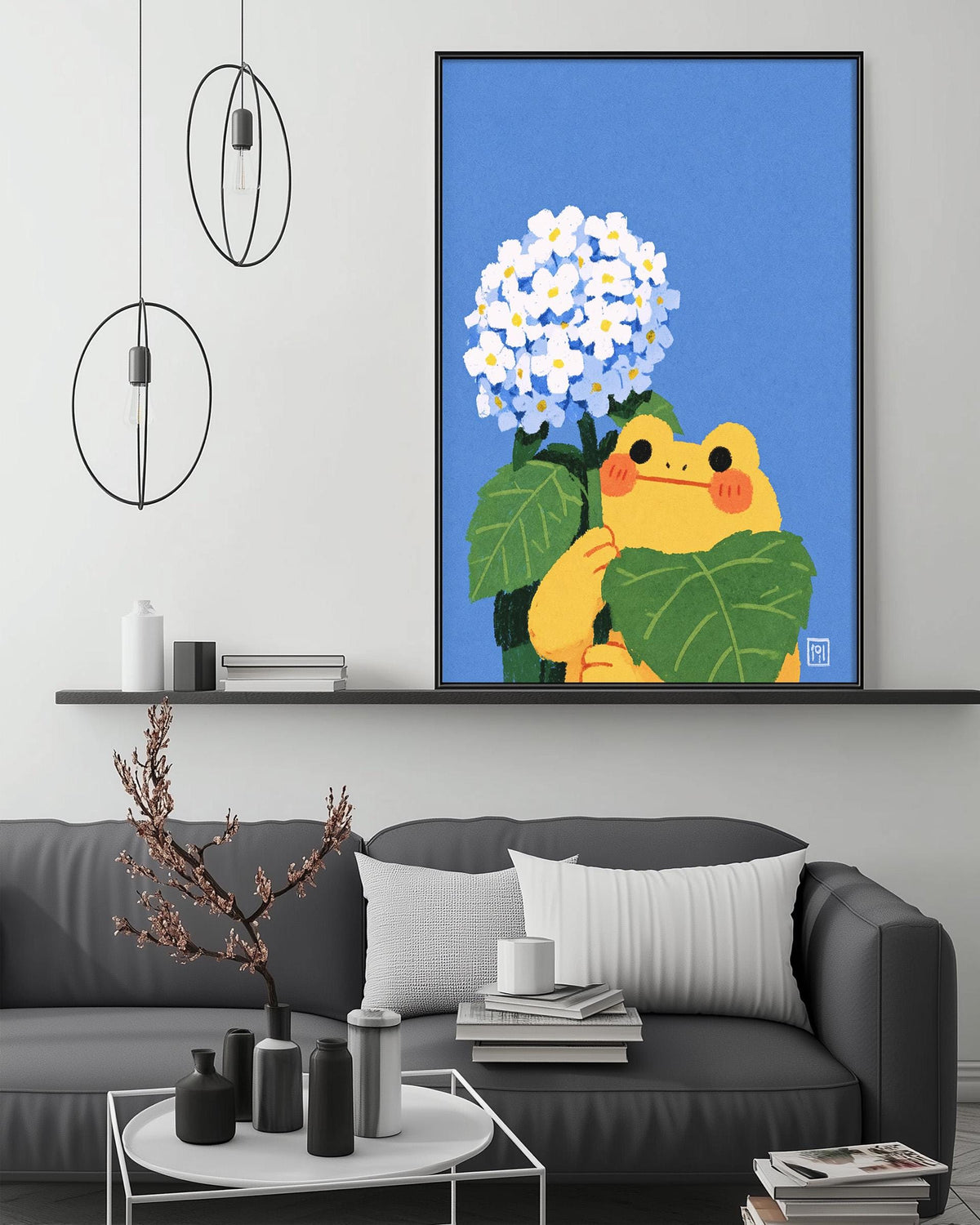 a cozy living room with a gray sofa, a coffee table, and a framed illustration of a frog holding a bunch of white flowers.