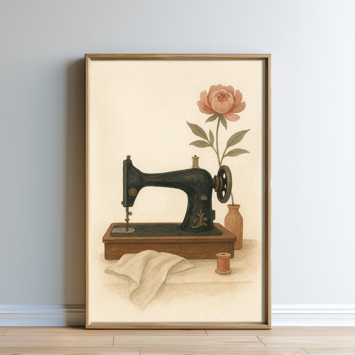 A framed painting depicting an old-fashioned sewing machine with a pink flower on the side, placed on a wooden surface against a white wall.
