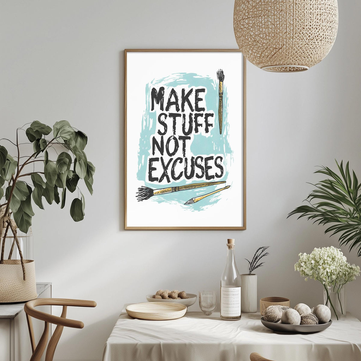 a framed poster with the text "MAKE STUFF NOT EXCUSES" hanging on a wall above a dining table with various items on it.