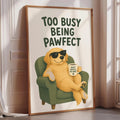 A framed poster with a cartoon dog sitting in a chair, wearing sunglasses and holding a coffee mug, with the text "Too Busy Being Pawfect" written above it.