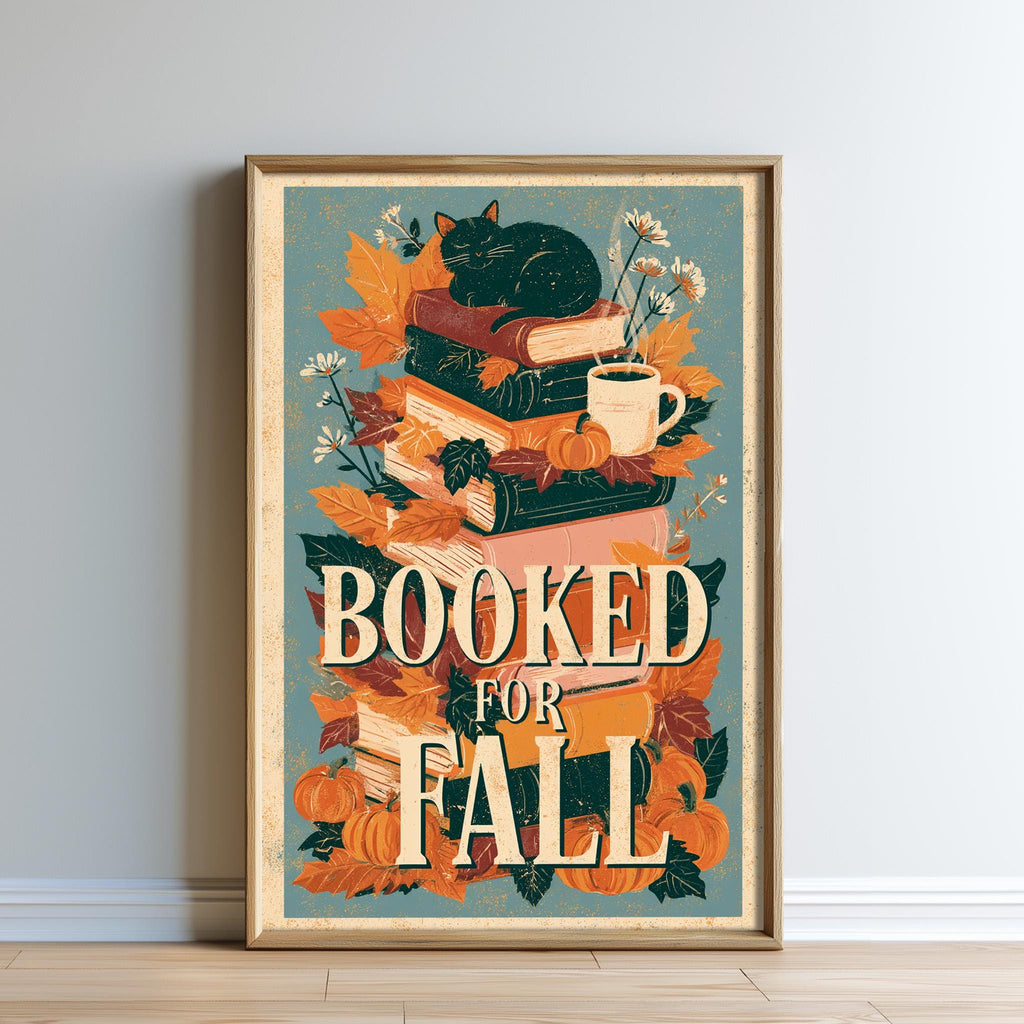 A framed poster with a black cat sitting on top of a stack of books, surrounded by autumn leaves, flowers, and a cup of coffee. The text "BOOKED FOR FALL" is prominently displayed in the center of the poster.