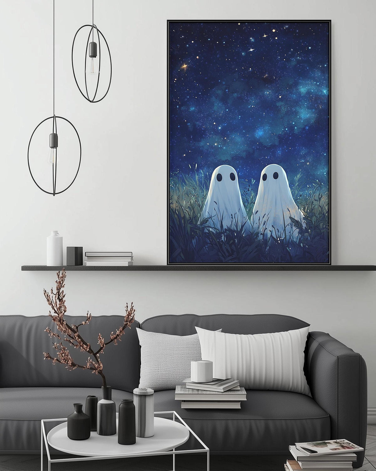 a cozy living room with a gray sofa, a coffee table, and a large framed picture of two ghostly figures gazing up at the night sky. The room has a minimalist and modern design, with a pendant light hanging above the sofa and a bookshelf filled with books and decorative items.