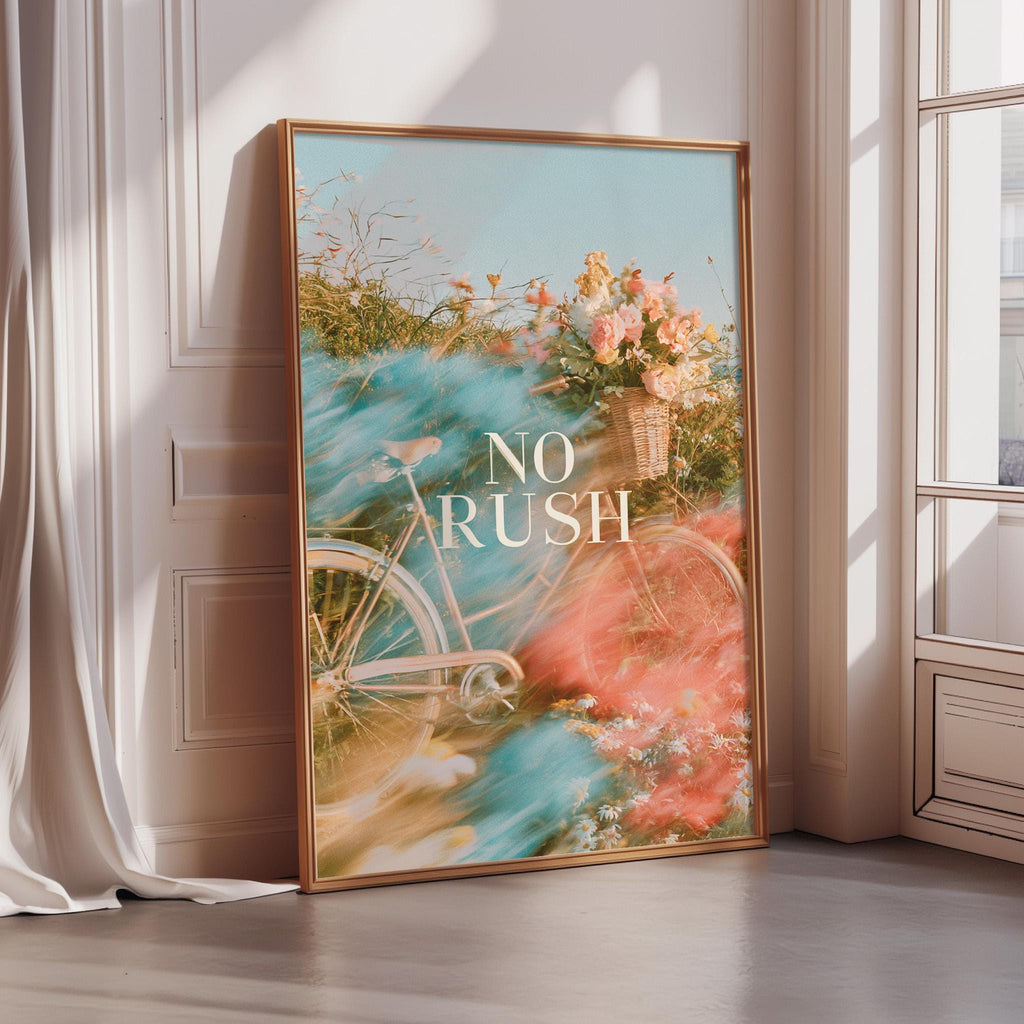 a large framed poster with a bicycle and flowers, placed on a wall near a window.