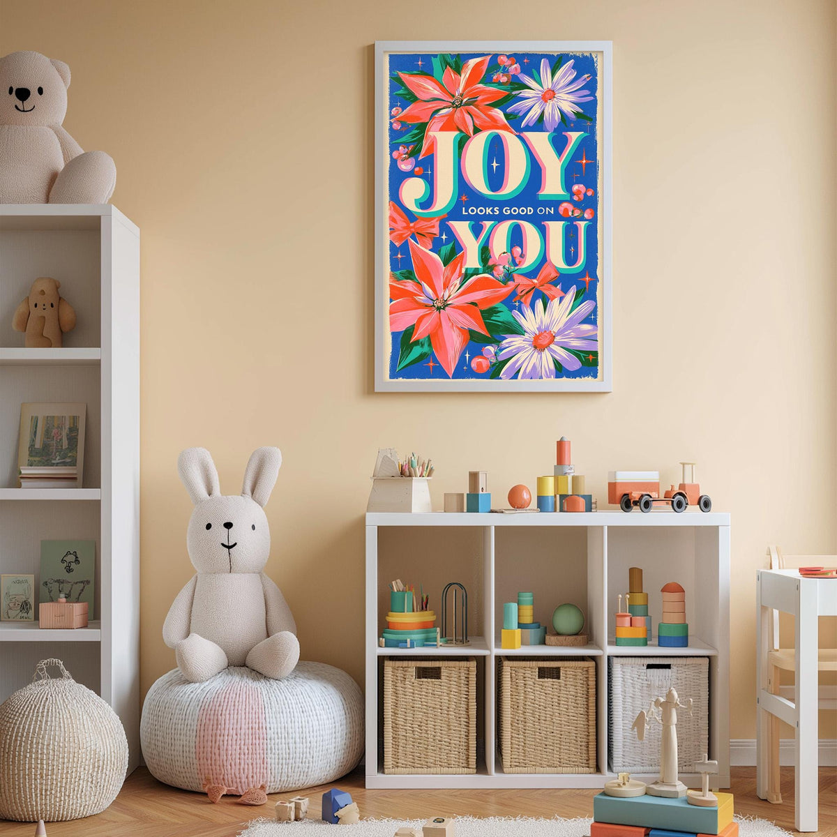A child's bedroom with a white bookshelf, a stuffed rabbit, and a colorful poster on the wall. The poster features the text "JOY LOOKS GOOD ON YOU" surrounded by flowers and other decorative elements.