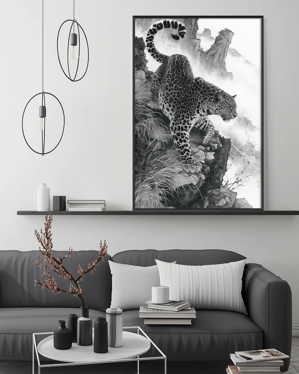 a large black and white photograph of a leopard on a rocky cliff, hanging on a wall above a gray couch with a coffee table in front of it.