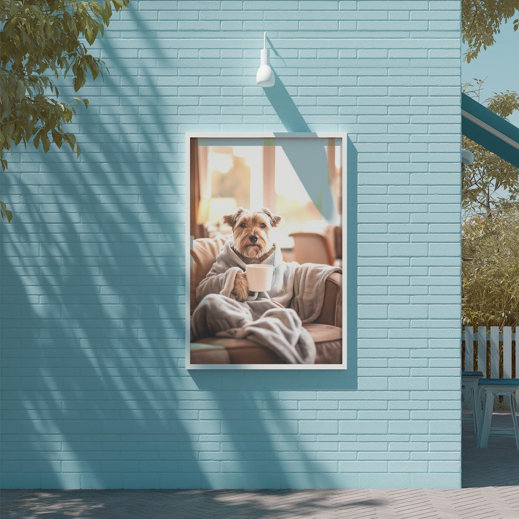 A dog is sitting on a couch, wrapped in a blanket, and holding a cup, as depicted in a framed image on a blue wall.