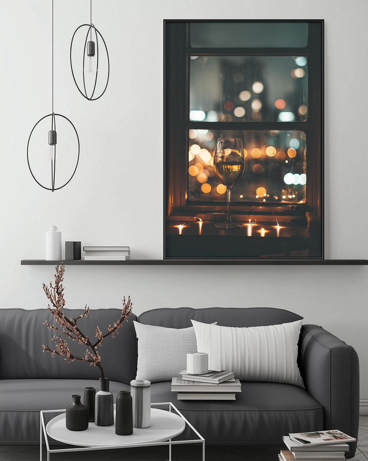 a modern living room with a gray sofa, a coffee table, and a large framed picture of a lit window with a glass of wine on the sill. The room has a minimalist and stylish design, with a black and white color scheme and a few decorative elements such as a potted plant and a stack of books.