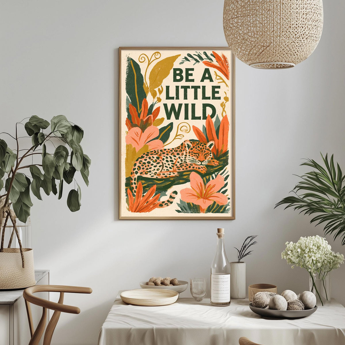 a framed poster with a leopard and tropical plants hanging on a wall above a dining table with various items on it.