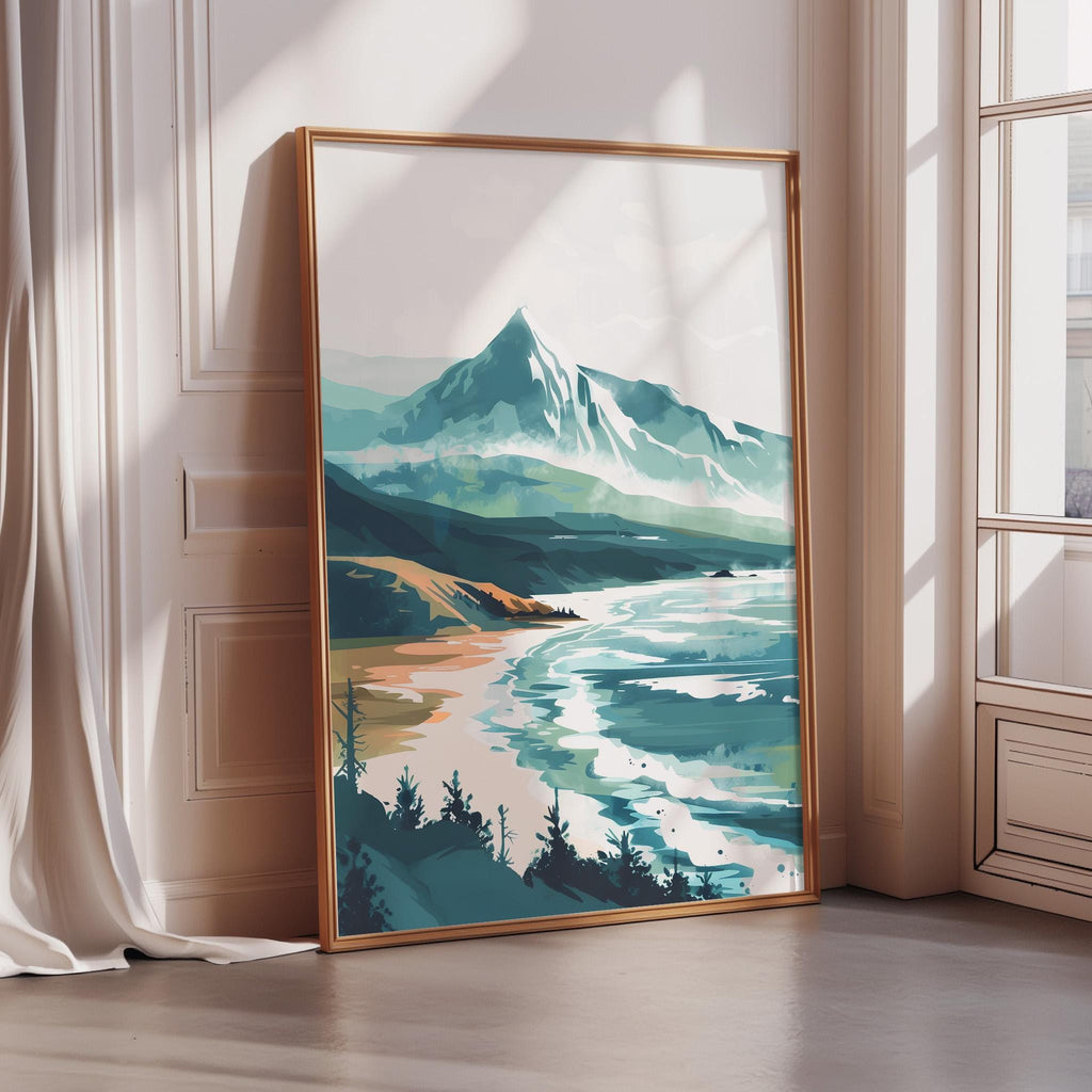 A large framed landscape painting depicting a serene mountain scene with a beach and ocean in the background.