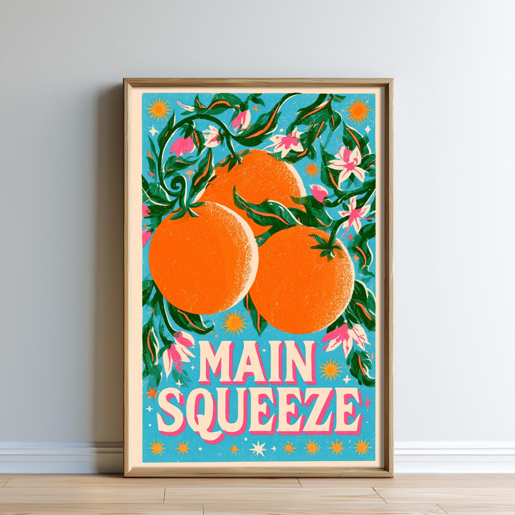 The image is a framed poster with a vibrant illustration of three oranges hanging from a branch with flowers. The text "MAIN SQUEEZE" is prominently displayed in the center of the poster.