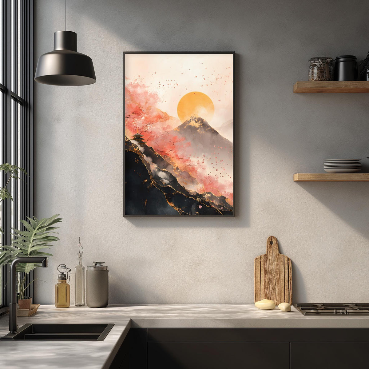 a kitchen counter with a framed painting of a mountain landscape hanging above it. The painting has a warm, orange and red color scheme, with a large sun in the sky. The kitchen counter has various items on it, including a cutting board, a bottle, and a bowl. The overall scene has a cozy, homey feel.
