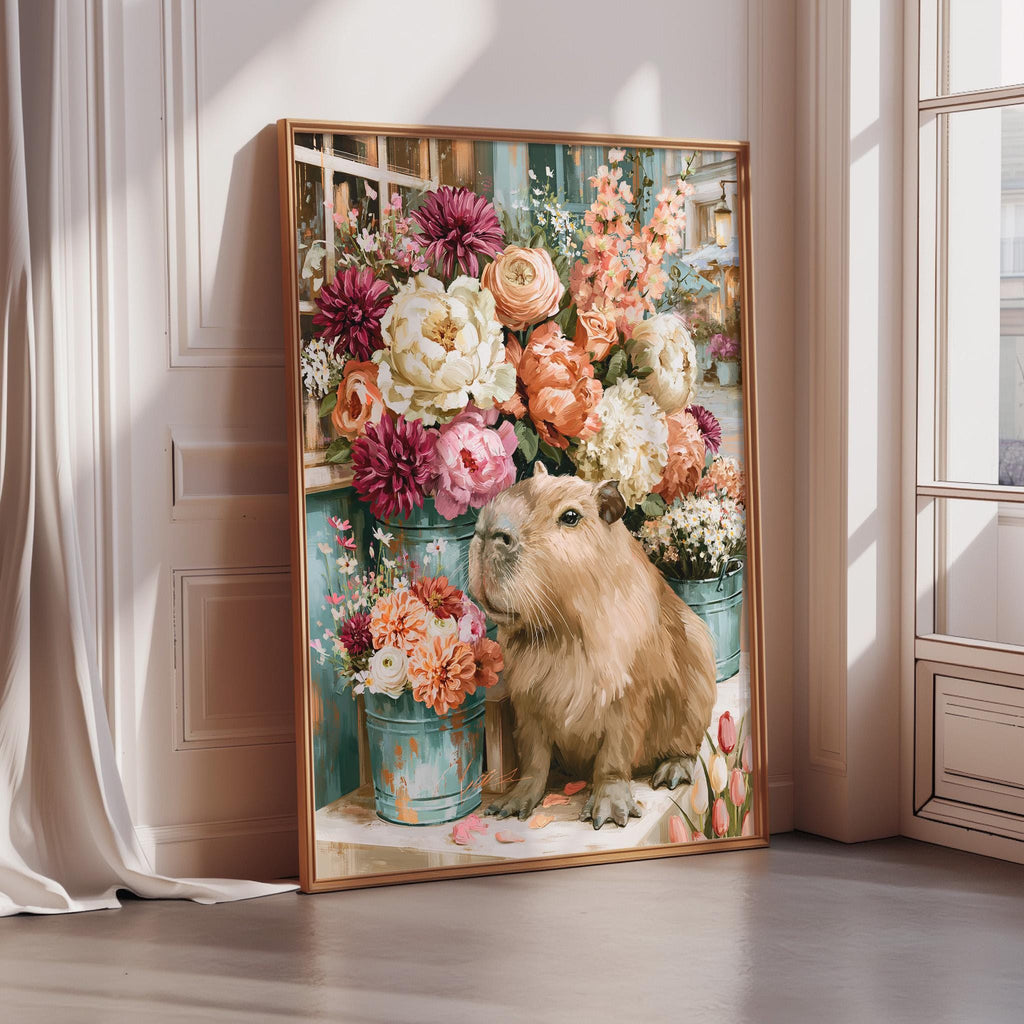A large framed painting depicting a beige capybara surrounded by a vibrant floral arrangement, including pink peonies, orange roses, and white lilies.