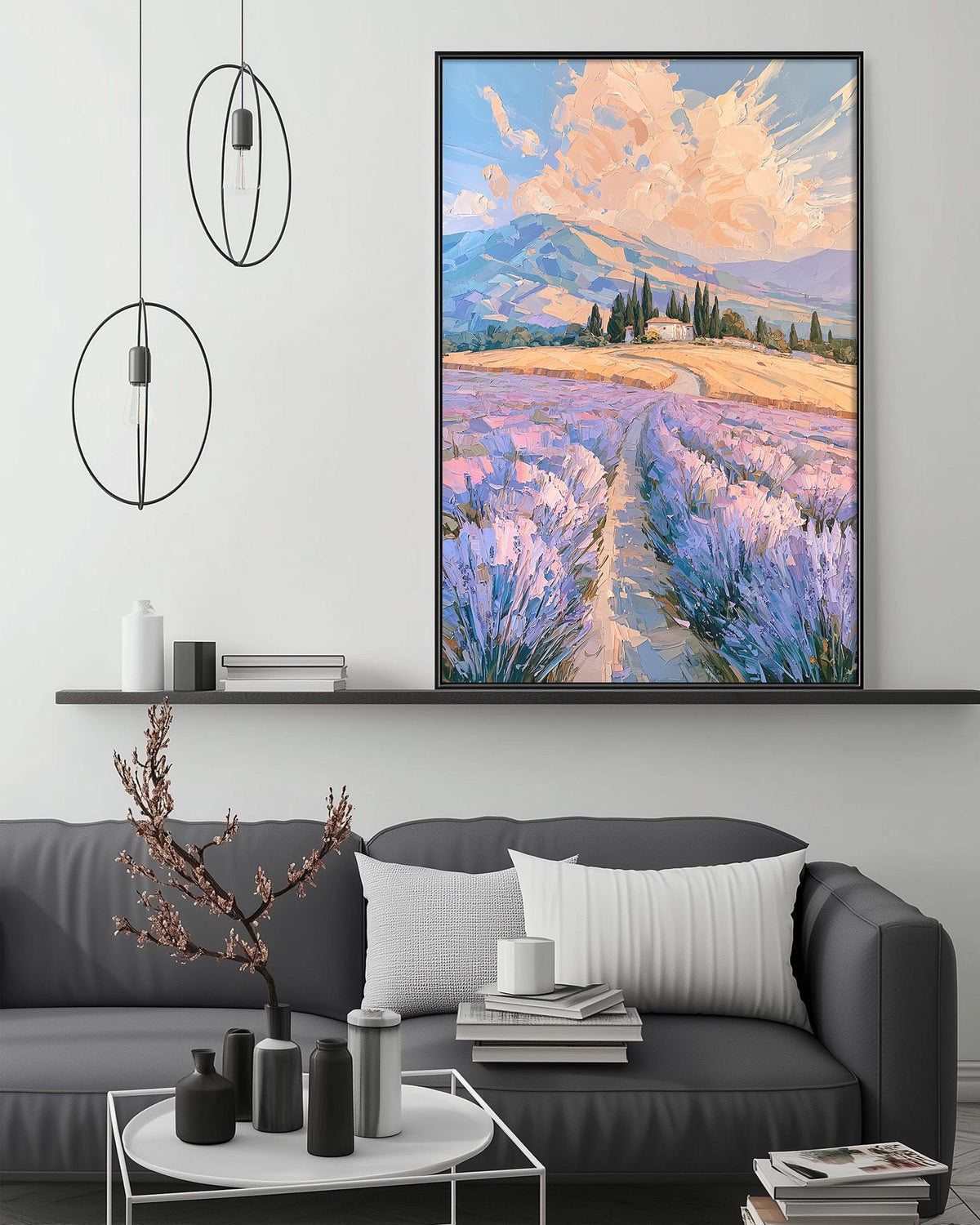 a living room with a gray sofa, a coffee table, and a large painting of a field with purple flowers hanging above it. The painting depicts a picturesque landscape with a winding path leading through the field.