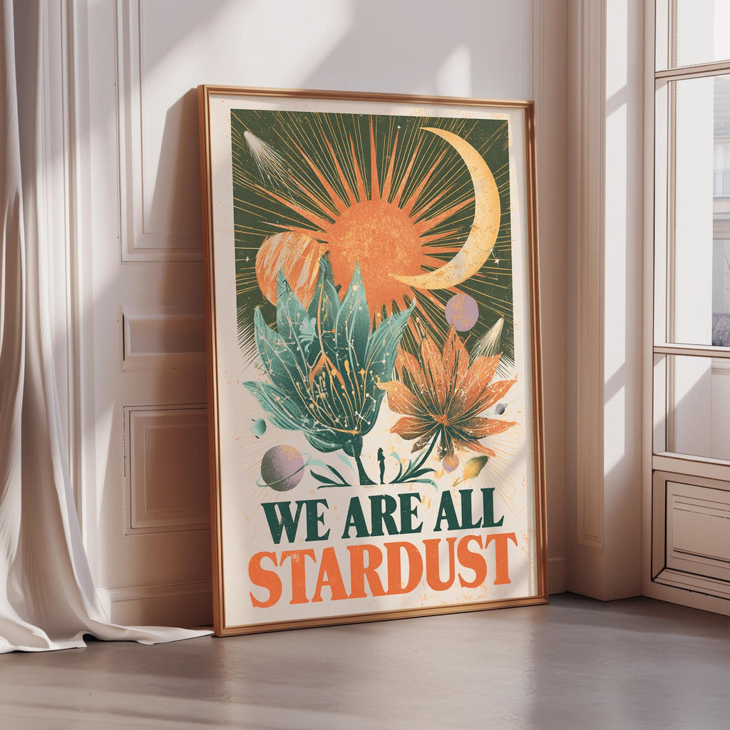 A framed poster with a vibrant, colorful design featuring a crescent moon, sun, and various flowers and plants. The text on the poster reads "WE ARE ALL STARDUST".