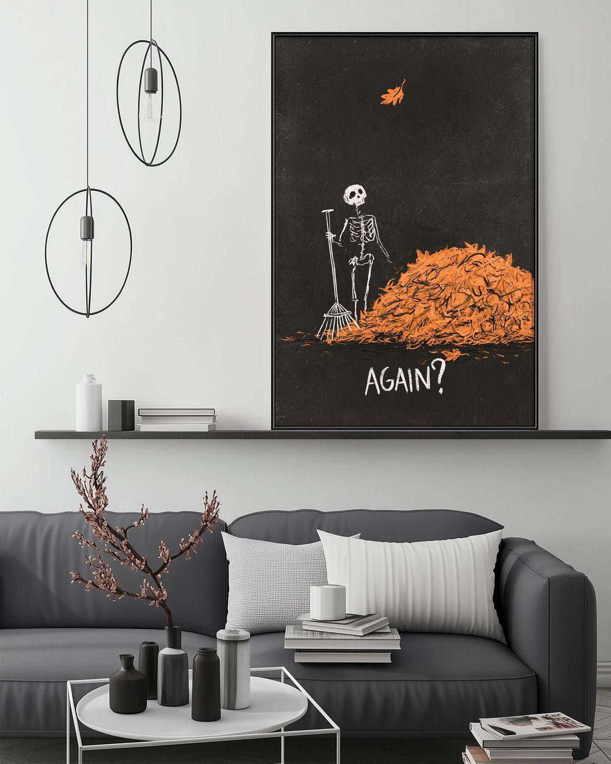 a living room with a gray sofa, a coffee table, and a large framed poster on the wall. The poster depicts a skeleton holding a broom and standing in front of a pile of orange leaves, with the word "AGAIN?" written below the image.