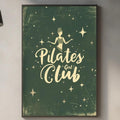 a kitchen counter with various kitchen items, including a cutting board, a sink, and a potted plant. Above the counter, there is a framed poster with the text "Pilates Club" and a starry background.