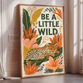 A framed poster with a leopard and tropical plants, featuring the text "Be a little wild".