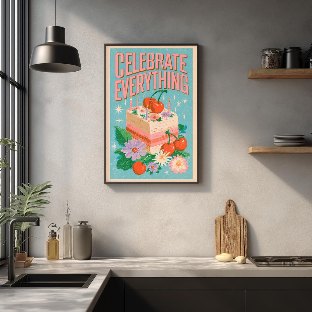 a kitchen counter with various kitchen items, such as a cutting board, a bottle, and a vase. Above the counter, there is a framed poster with a colorful illustration of a cake and flowers, along with the text "Celebrate Everything".