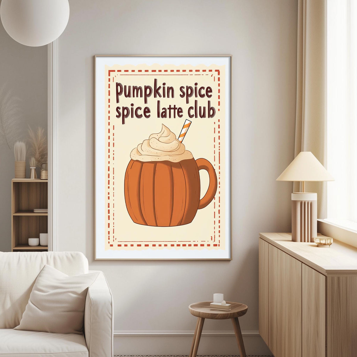 a cozy living room with a white couch, a wooden side table, and a lamp. A framed poster on the wall displays an illustration of a pumpkin spice latte with whipped cream, accompanied by the text "Pumpkin spice spice latte club".