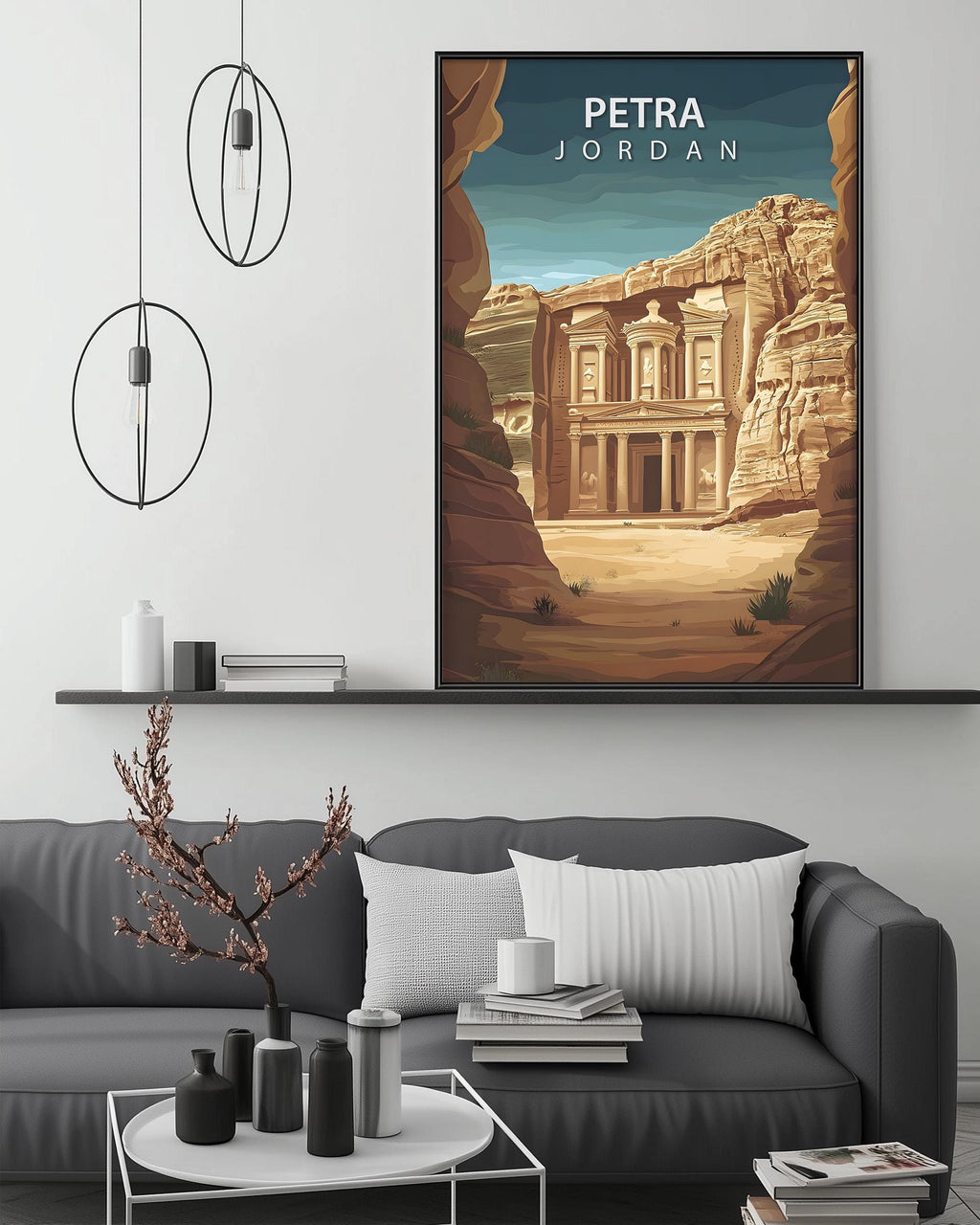 a large framed poster of the Petra rock carving in Jordan, hanging on a wall above a gray couch with a coffee table in front of it.