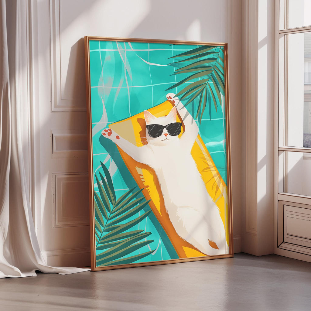 A framed illustration of a cat lounging on a yellow towel, wearing sunglasses, and surrounded by tropical foliage.