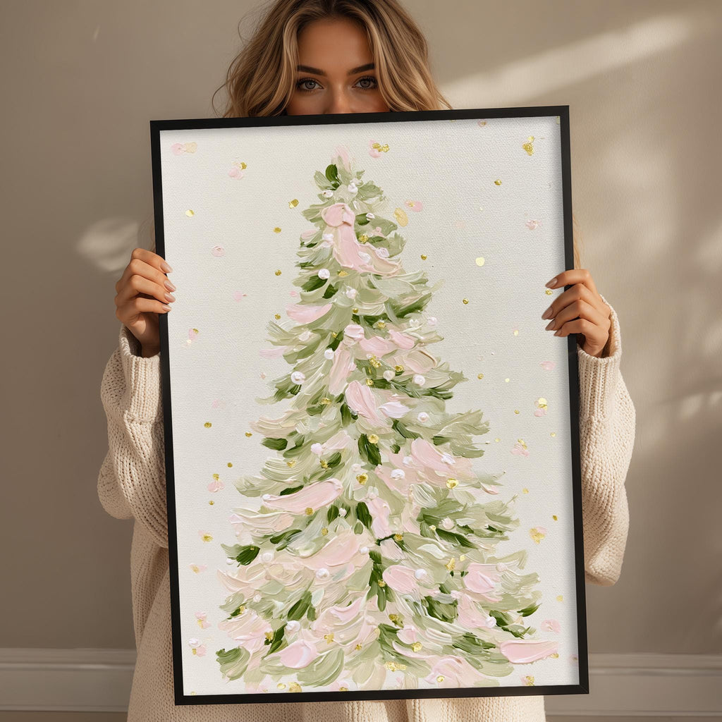 A woman holding a framed painting of a Christmas tree with pink and green leaves.