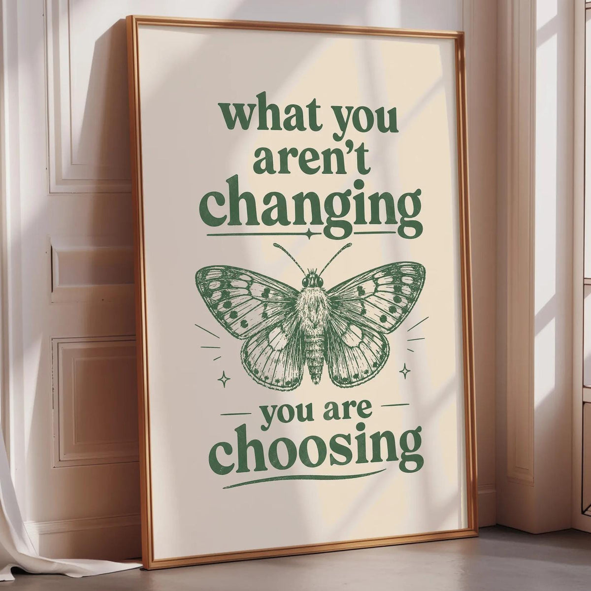 A framed poster with the text "what you aren't changing, you are choosing" and an illustration of a butterfly.