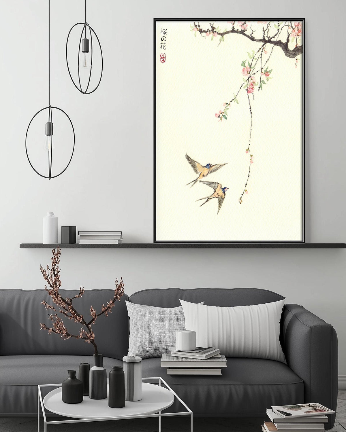 a modern living room with a gray sofa, a coffee table, and a large framed artwork depicting two birds in flight above a branch with pink flowers.