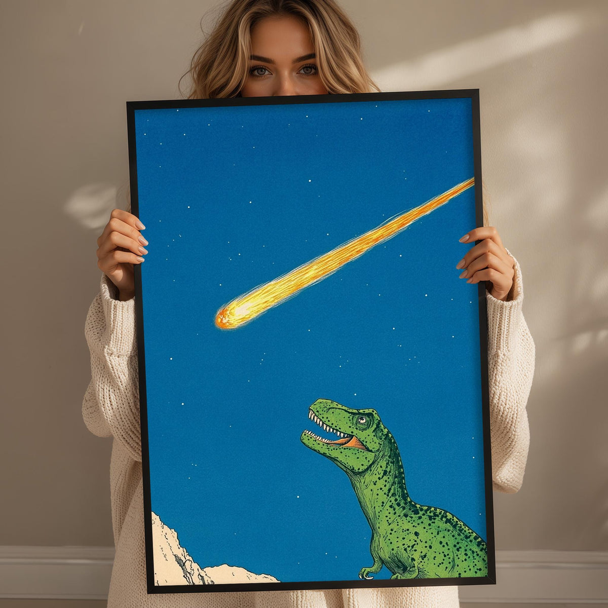 A woman holds up a framed illustration of a green dinosaur against a blue sky with a bright yellow meteor streaking across it.