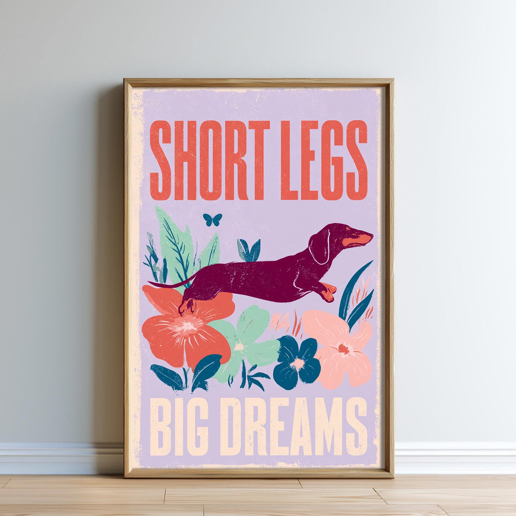The image is a framed poster with a dachshund dog and colorful flowers, along with the text "SHORT LEGS BIG DREAMS".