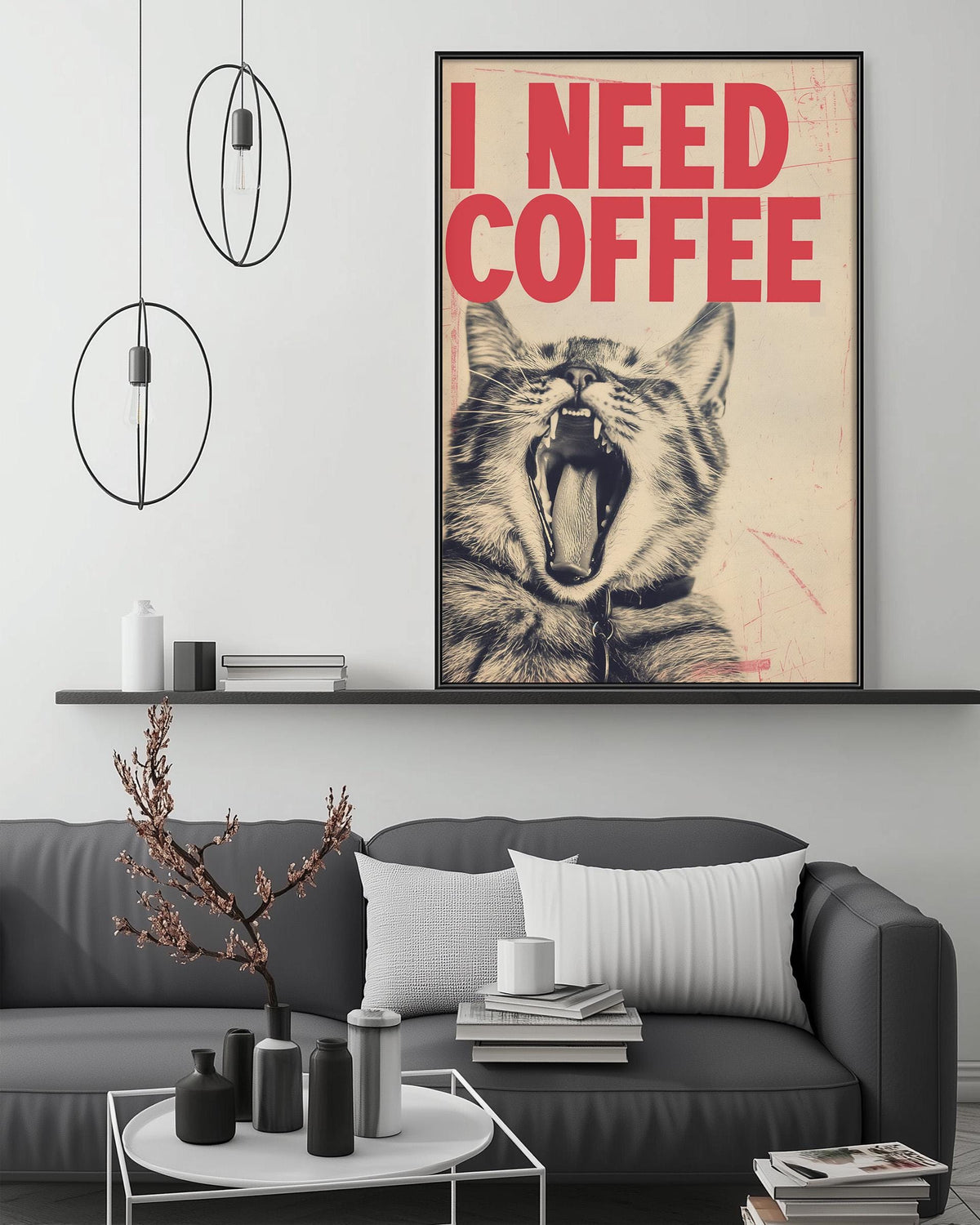 a gray couch with a coffee table in front of it, and a framed poster of a cat with its mouth open, displaying the text "I NEED COFFEE".