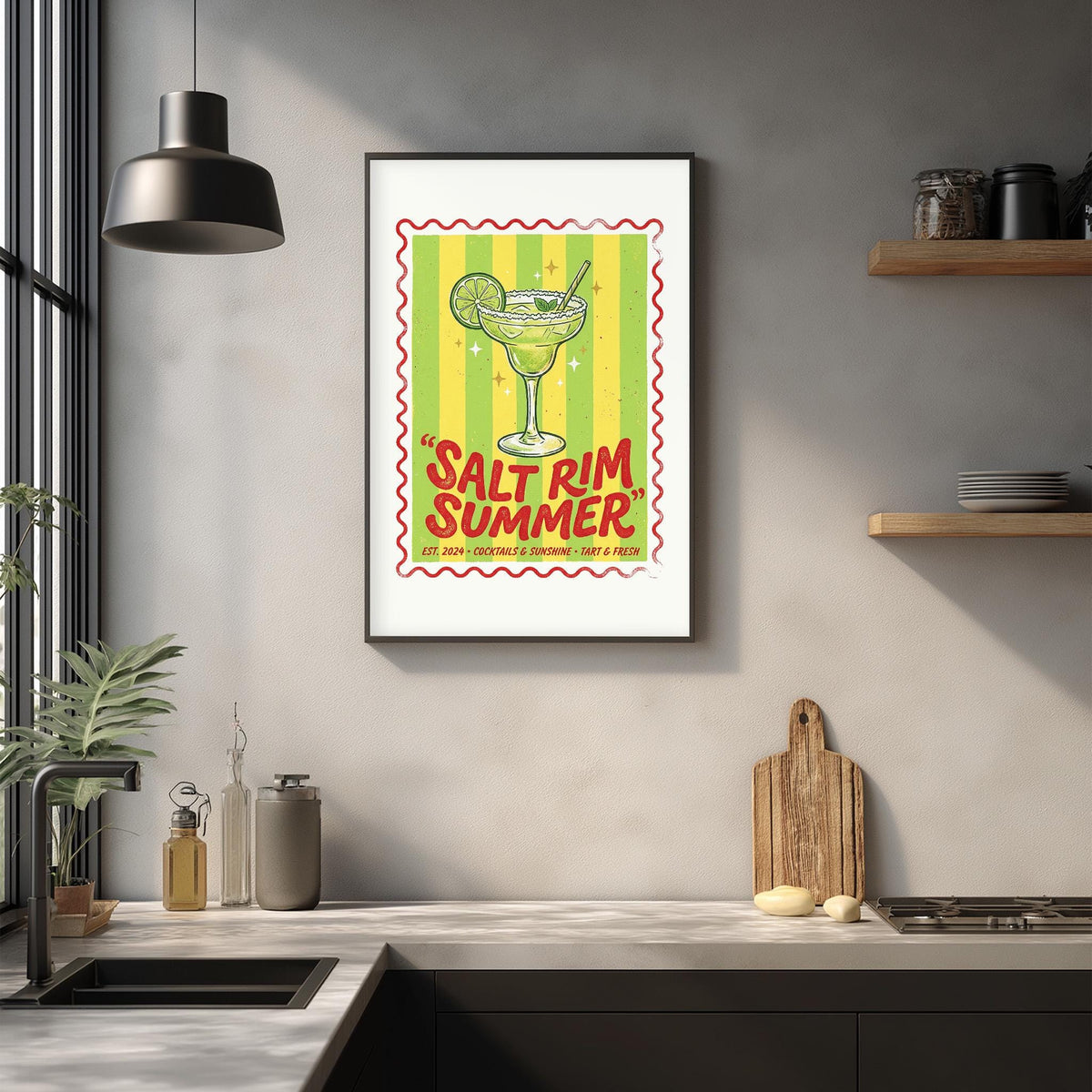 a framed poster of a margarita glass with the text "Salt rim summer" on it, hanging on a wall above a kitchen counter with various kitchen items and decor.