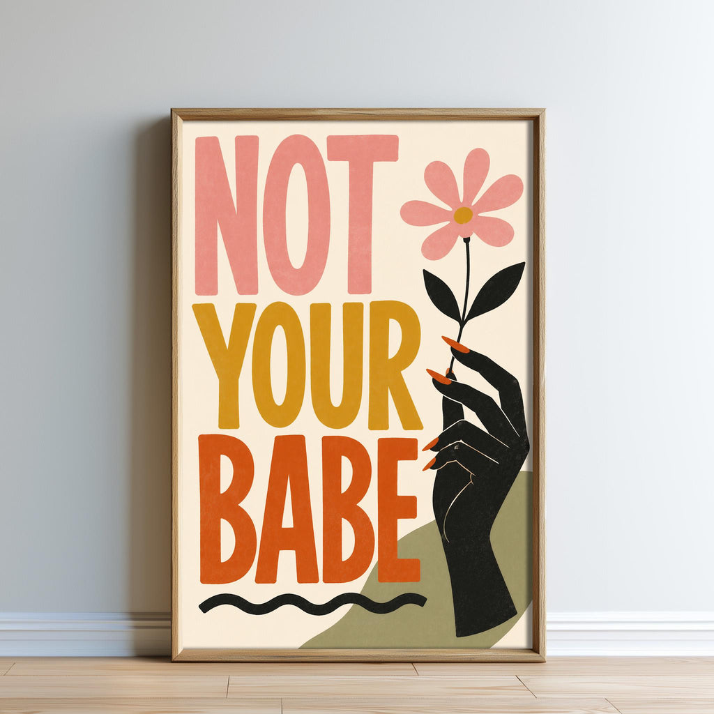 The image is a framed poster with a hand holding a flower and the text "NOT YOUR BABE" written on it.