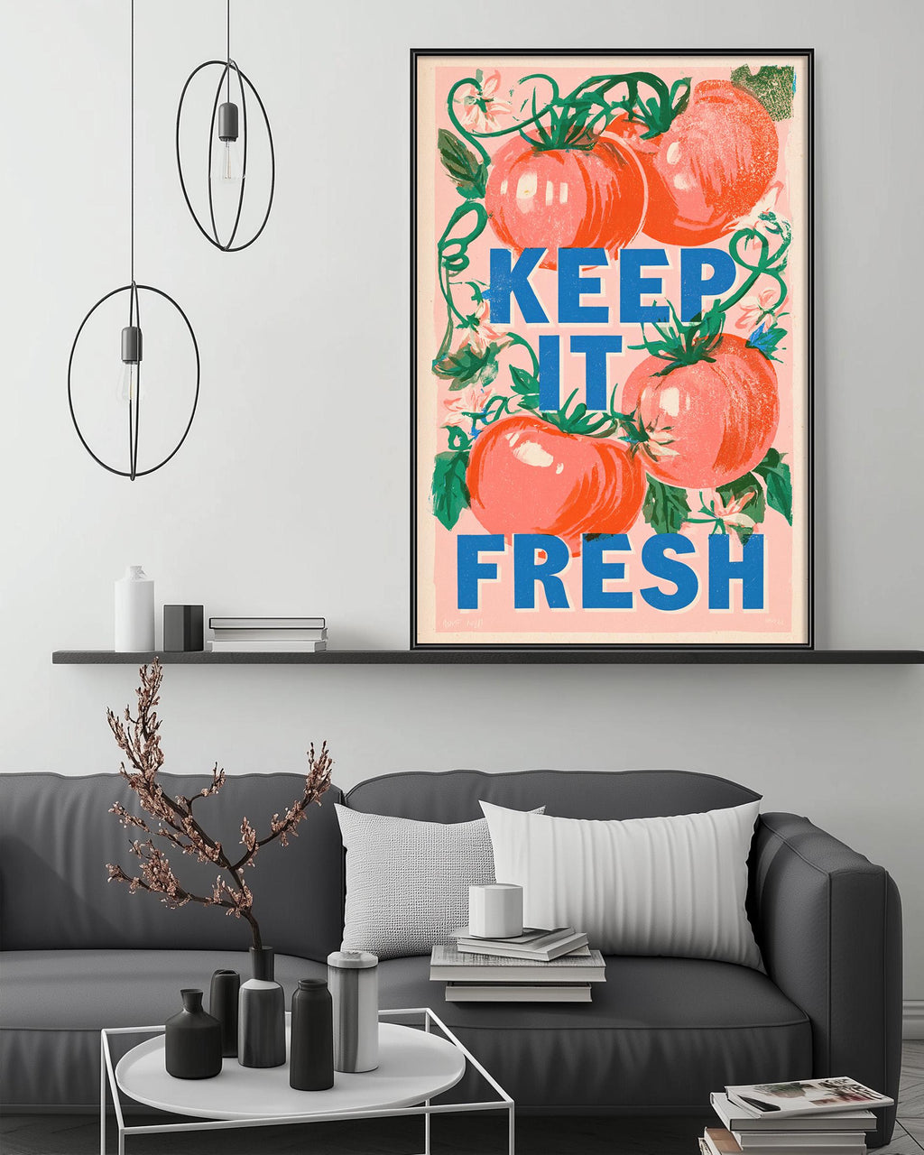 a large framed poster with the text "KEEP IT FRESH" in bold letters, surrounded by illustrations of tomatoes and leaves. The poster is displayed on a wall above a gray couch, which has a coffee table in front of it. The room also contains a shelf with various decorative items, and a potted plant is visible in the background.